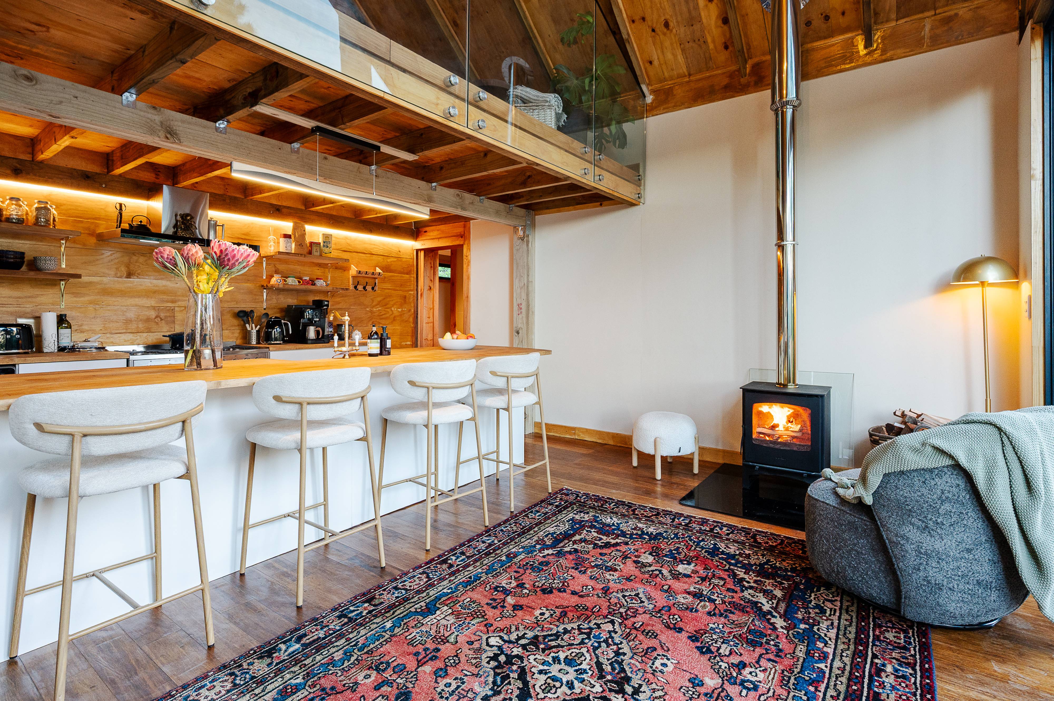 A warm timber kitchen with a bar and a wood burning stove