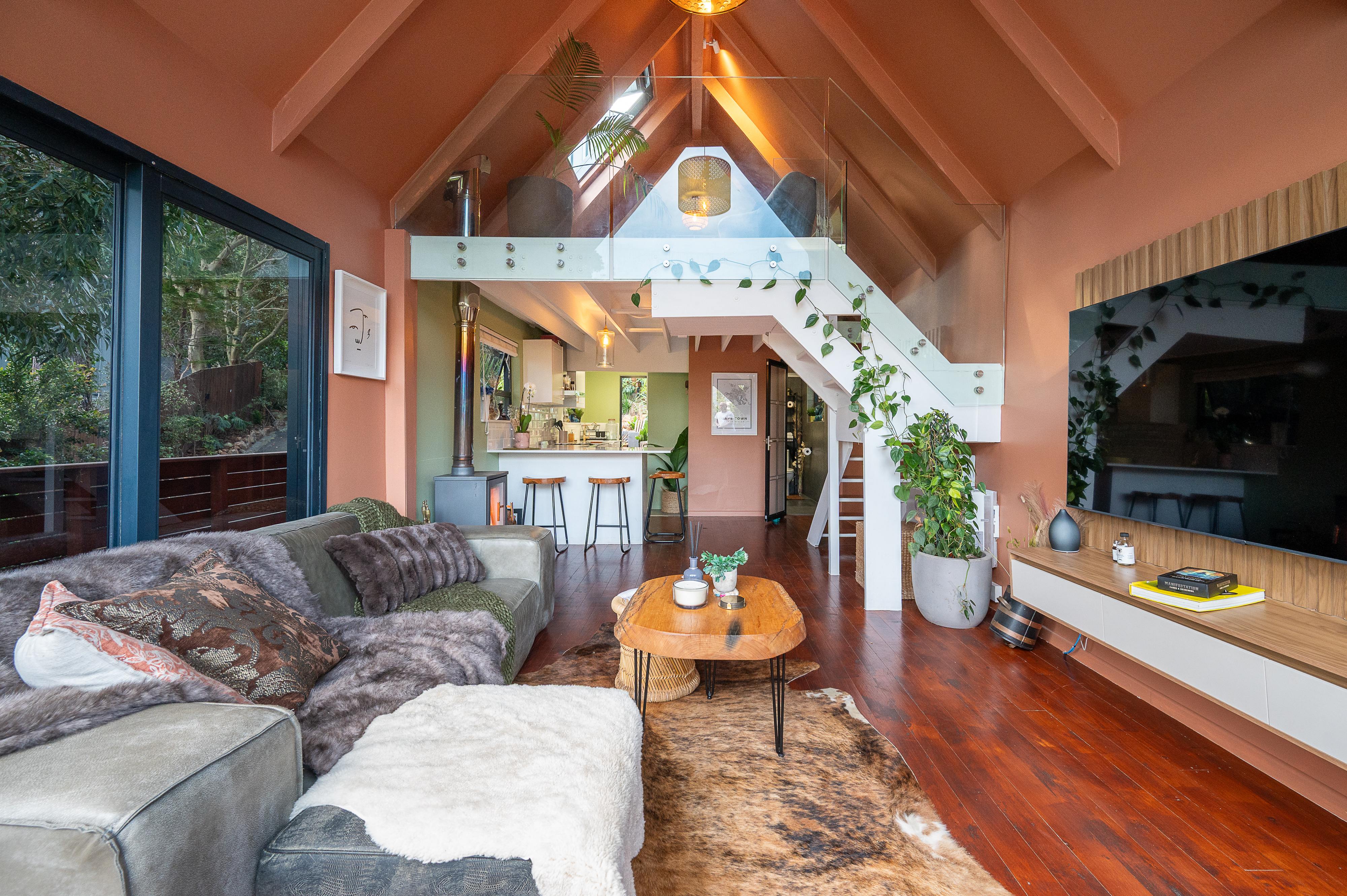 Open living space with a vaulted ceiling, mezzanine loft and white staircase